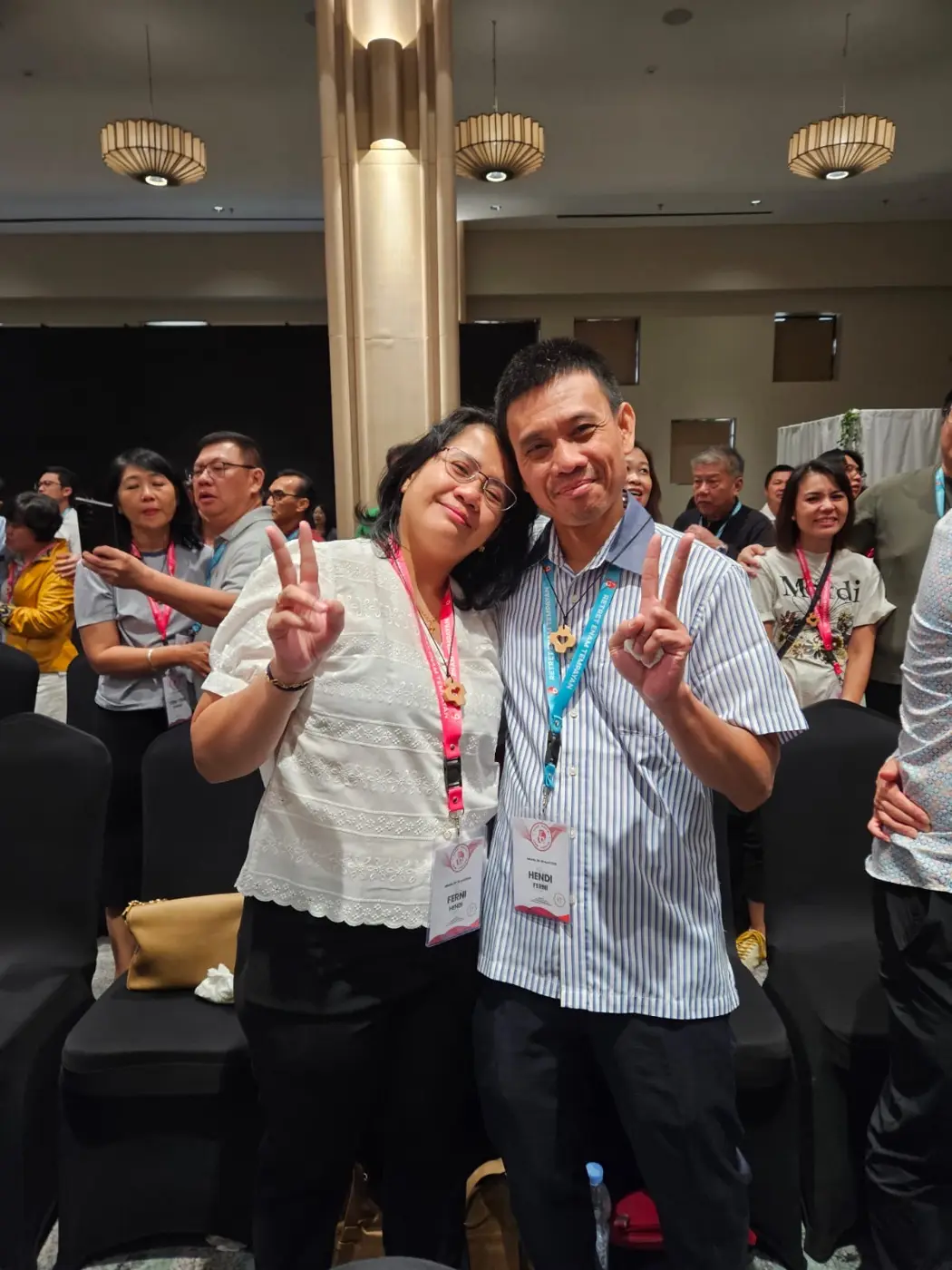 Suami-istri alumni bersandar satu sama lain dan tersenyum